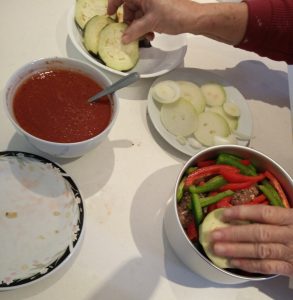 Layering the Tepsi Baytinijan in the cooking pot